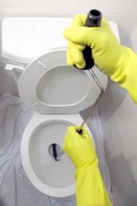 North Miami Beach plumbing technician clears a toilet drain with a hand augur